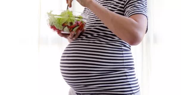 Беременная женщина ест салат — стоковое видео