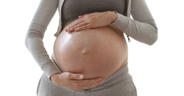 Беременная женщина с помощью крема для растяжки живота — стоковое фото