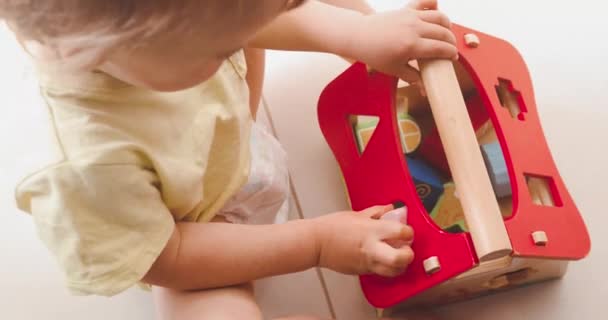 Lindo niño jugando con una pequeña casa de madera — Vídeo de stock