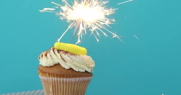 振りかけると線香花火の青い背景のカップケーキ — ストック動画