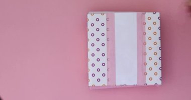 El ile pembe üzerinde renkli donut kutusunu aç