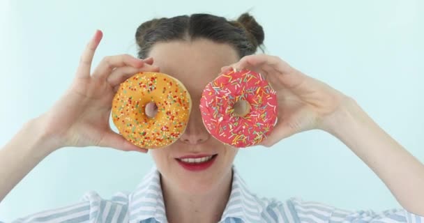 Жінка бере пончики і робить сонцезахисні окуляри з нього — стокове відео