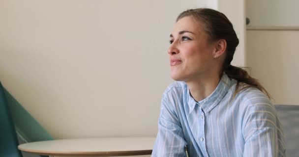 Joyeux jeune femme assise sur une chaise et regardant loin — Video