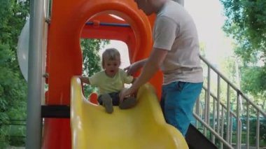Bebek aşağı kayar slayt baba sigortalanır ve yardımcı olur