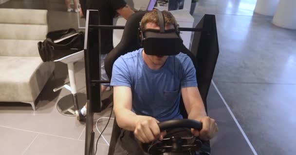 Hombre en VR juego de auriculares simulador de coche y juega carreras — Vídeos de Stock