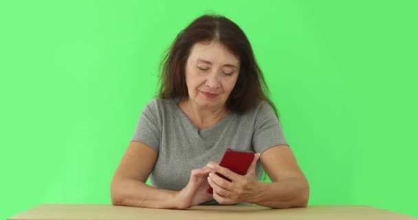 Взрослая женщина, использующая телефон в хромакеи — стоковое видео