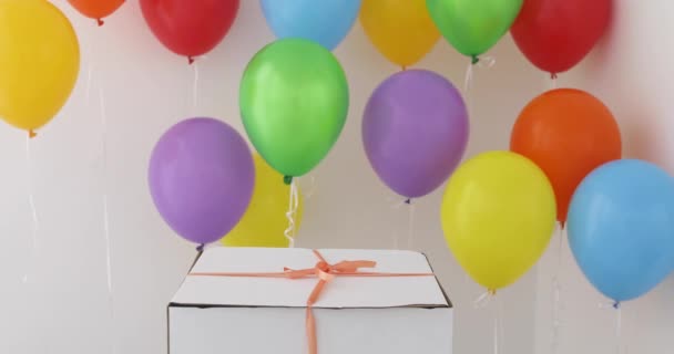 Белая подарочная коробка с красной лентой и цветным воздушным шаром — стоковое видео