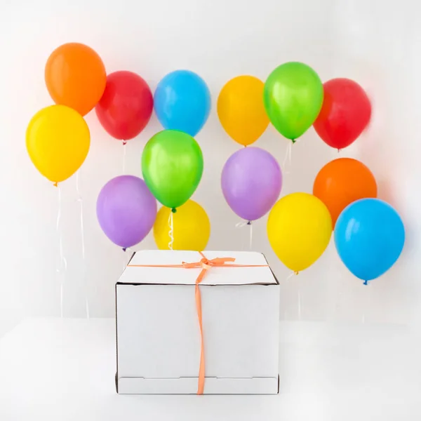 White gift box with red ribbon and colorful balloon — Stock Photo, Image