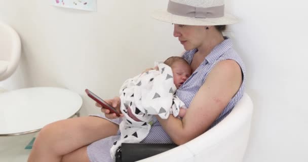 Kvinna med baby med smartphone — Stockvideo