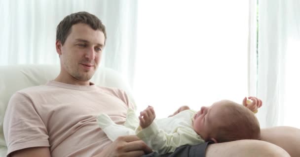 Содержательный мужчина сидит с ребенком на коленях — стоковое видео