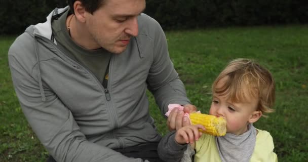 Father feeding his baby with a corn — Stock Video