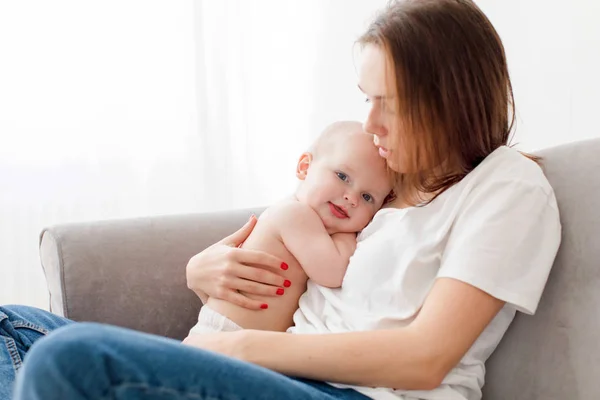 Madre che abbraccia il bambino sul divano — Foto Stock