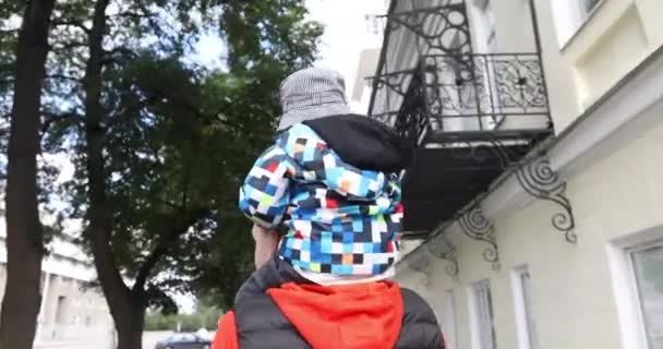 Vader geven zoon piggyback ritje op zijn schouders achteraanzicht — Stockvideo