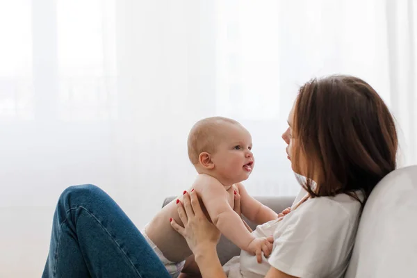 Young woman talking to baby on sofa — Stock Photo, Image