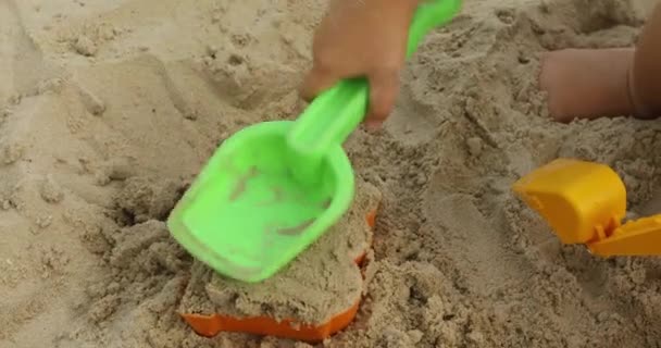 Nahaufnahme einer Kinderhand, die Sandspielzeug spielt — Stockvideo