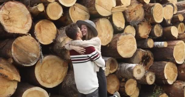 Пара объятий возле стопки бревен — стоковое видео