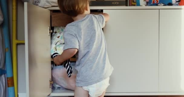 Blond toddler próbuje otworzyć drzwi szafki — Wideo stockowe