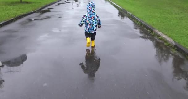 Bonito menino está correndo na poça — Vídeo de Stock