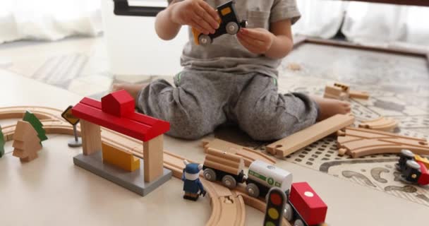 Дворічний хлопчик грає з дерев'яною залізницею — стокове відео