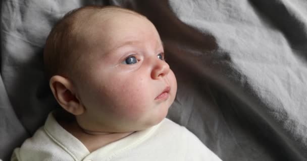 Bebé se acuesta en la espalda con los ojos grandes abiertos — Vídeo de stock