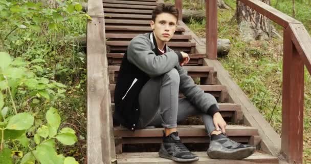 Jongeman zit op trap in bos — Stockvideo