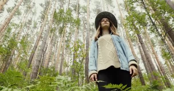 Giovane donna in piedi nella foresta con alberi alti — Video Stock