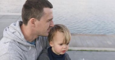 İskelede bebekle oturan genç adam