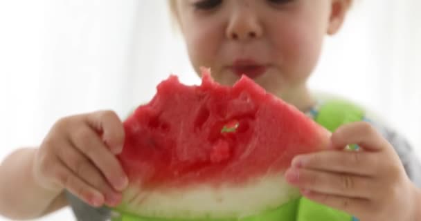 Liten unge pojke äter vattenmelon på tabell — Stockvideo