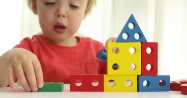 Çocuk bir ev inşa. Masada oturan ve beyaz arka plan üzerinde renkli Oluşturucu bloklarla oynama sevimli bebek çocuk