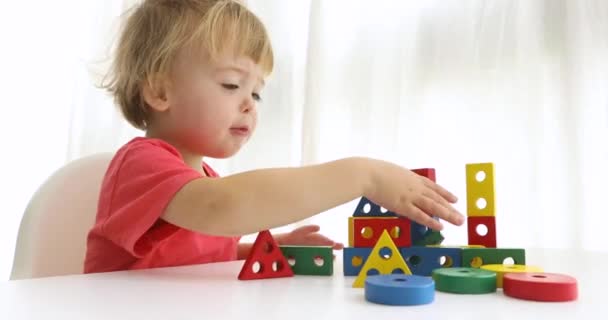 Renkli blok ile oynarken küçük çocuk inşa edilmiş bir ev yok eder. — Stok video