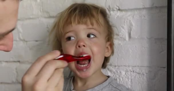 Родитель чистит зубы своему мальчику — стоковое видео