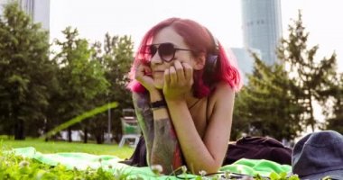Kızıl saçlı yalan ve rahatlatıcı park çim ile kız