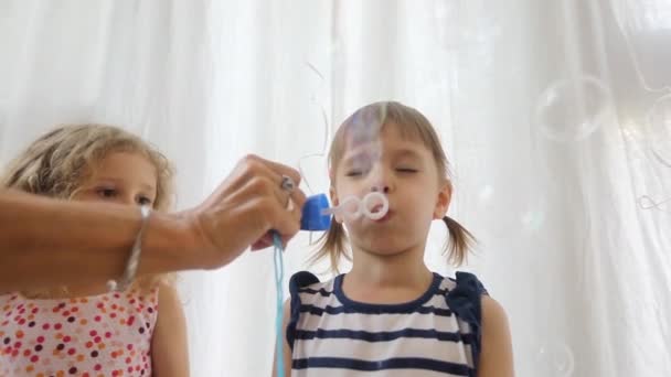 Cute little girl is blowing soap bubbles — Stock Video