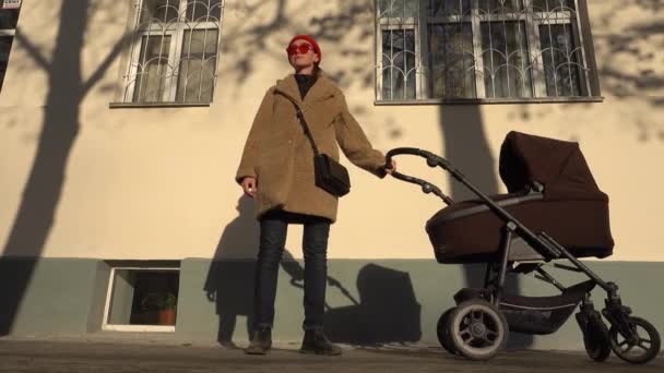 Vrouw met een kinderwagen gaat in de stad — Stockvideo