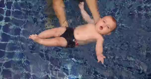 Menino nadando na piscina com os pais — Vídeo de Stock