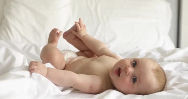 Charmantes glückliches Baby auf weißem Bett — Stockvideo
