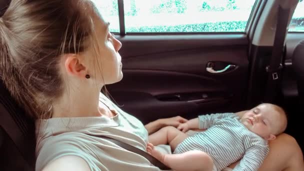 Mujer en coche con un bebé durmiendo en sus piernas — Vídeos de Stock