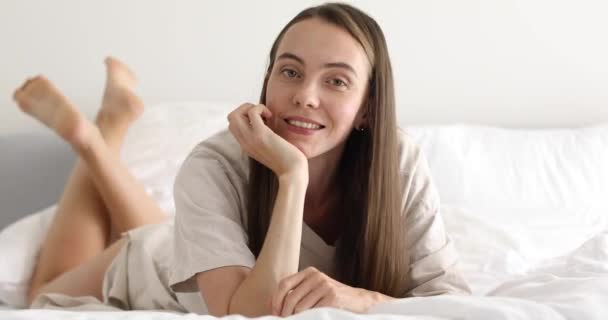 Чувственная молодая женщина лежит на кровати — стоковое видео