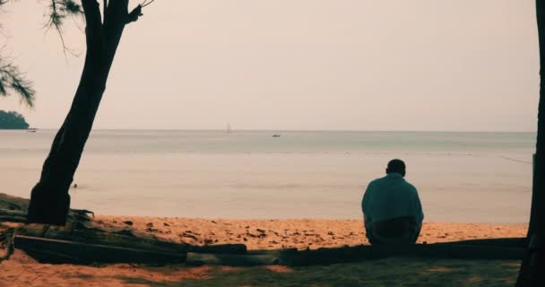 Uomo anonimo seduto sulla spiaggia di sabbia — Video Stock