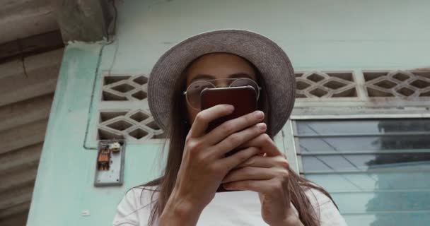 Stijlvolle vrouw met behulp van smartphone in de buurt van shabby gebouw — Stockvideo