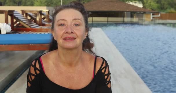 Atractiva sonriente mujer madura cerca de la piscina — Vídeo de stock