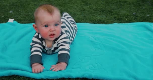 Cute baby lying on towel on lawn — Stock Video