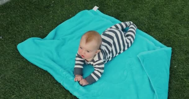 Lindo bebé acostado en la toalla en el césped — Vídeo de stock