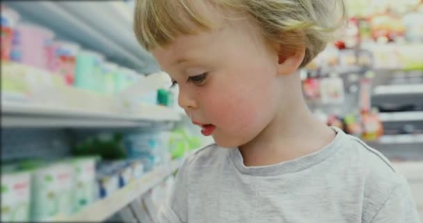 Kleiner, kinderblonder Junge beim Einkaufen im Supermarkt — Stockvideo