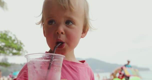 Miúdo engraçado a beber na praia — Vídeo de Stock