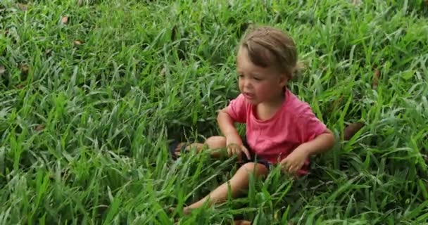 Verärgertes Baby sitzt auf Gras — Stockvideo