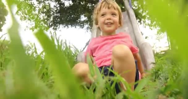 Очаровательный мальчик на детской площадке в зеленом парке — стоковое видео