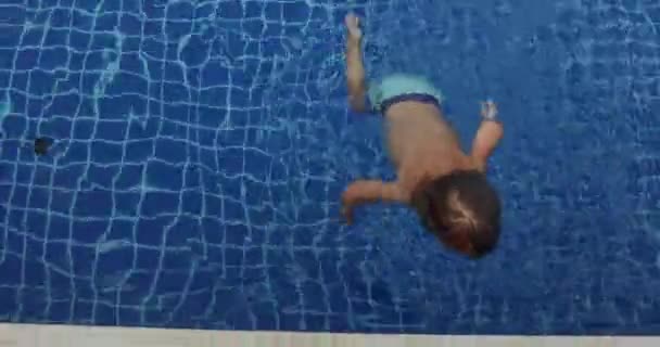 Glimlachend jongetje in water in de buurt van de rand van zwembad — Stockvideo