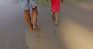 Genç adam ve küçük çocuk güneşli havalarda Kum Plajı üzerinde yürüyen kırpma bacaklar yukarıda