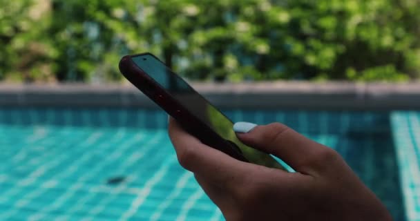 Crop hand using smartphone near swimming pool — Stock Video